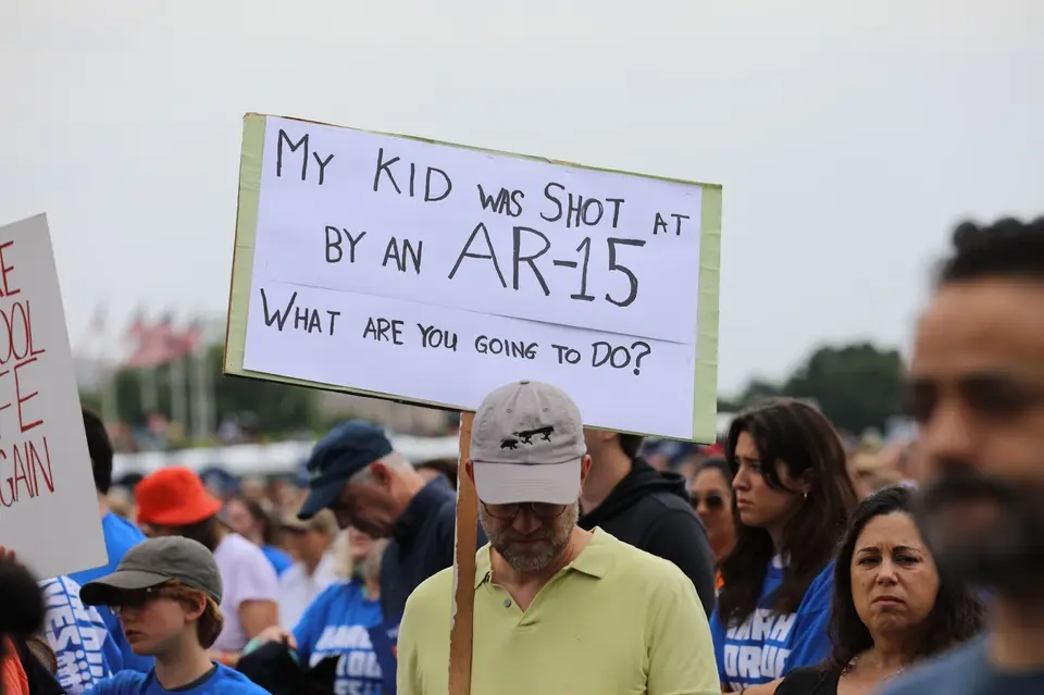 Survivor at the March for our lives 2022 rally holds up a sign stating my kid was shot by an ar 15