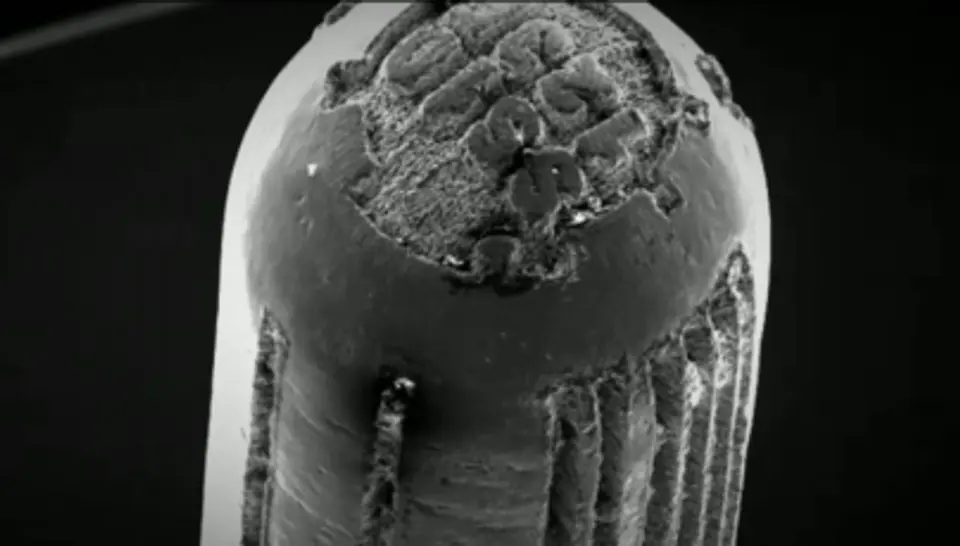 A microscopic, black and white photo that shows the engravings of firearm microstamping on a bullet.